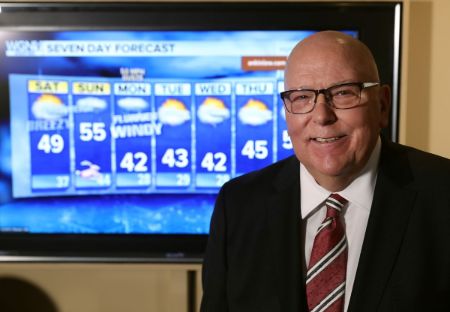 Tom Skilling in a black suit and red tie caught on the camera.